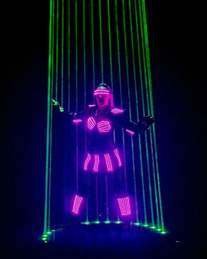 Artiest in een LED-pak omringd door groene laserstralen tijdens de act van Duo Lugo