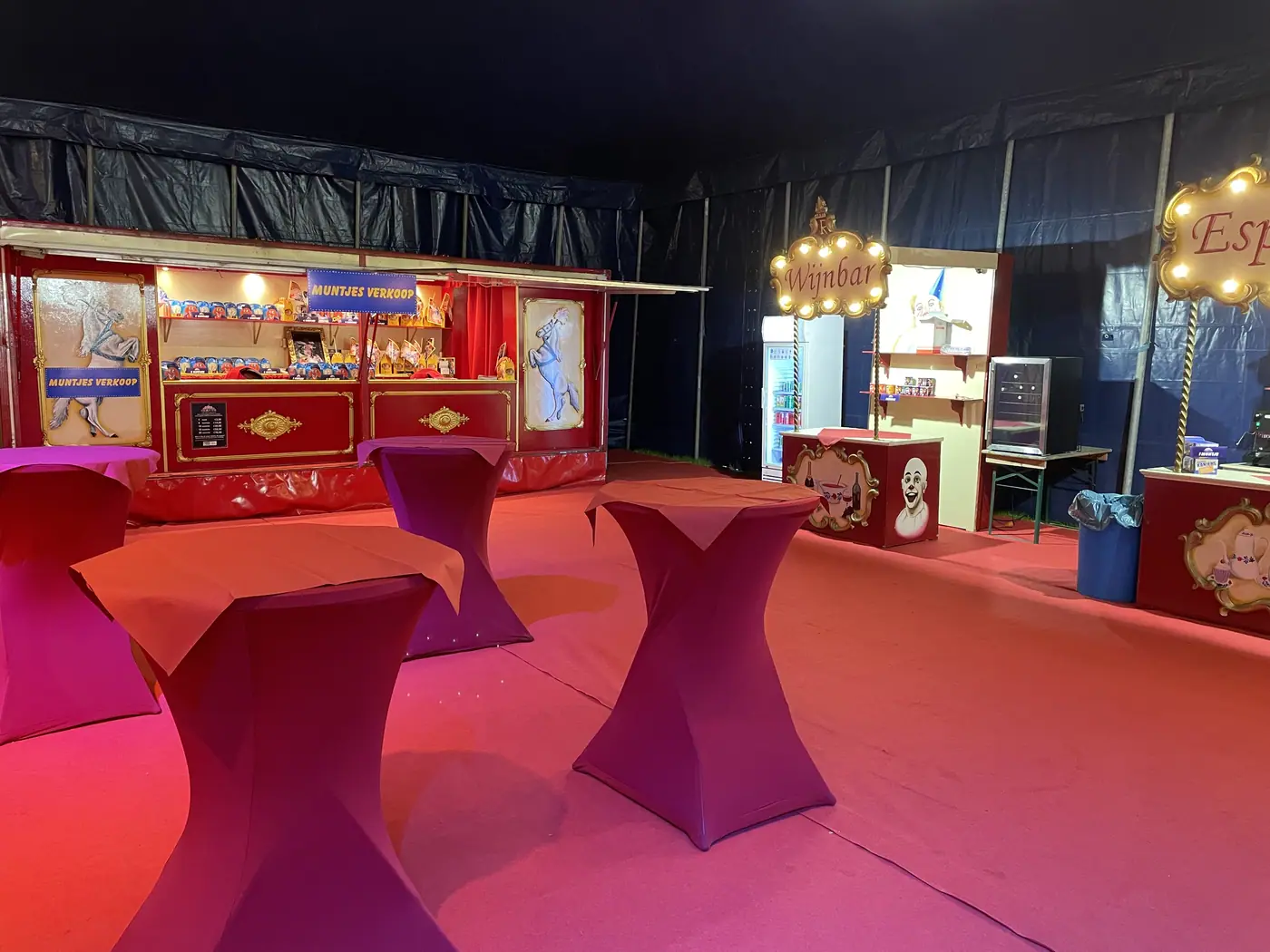 Rode statafels en verlichte kraampjes in de foyertent