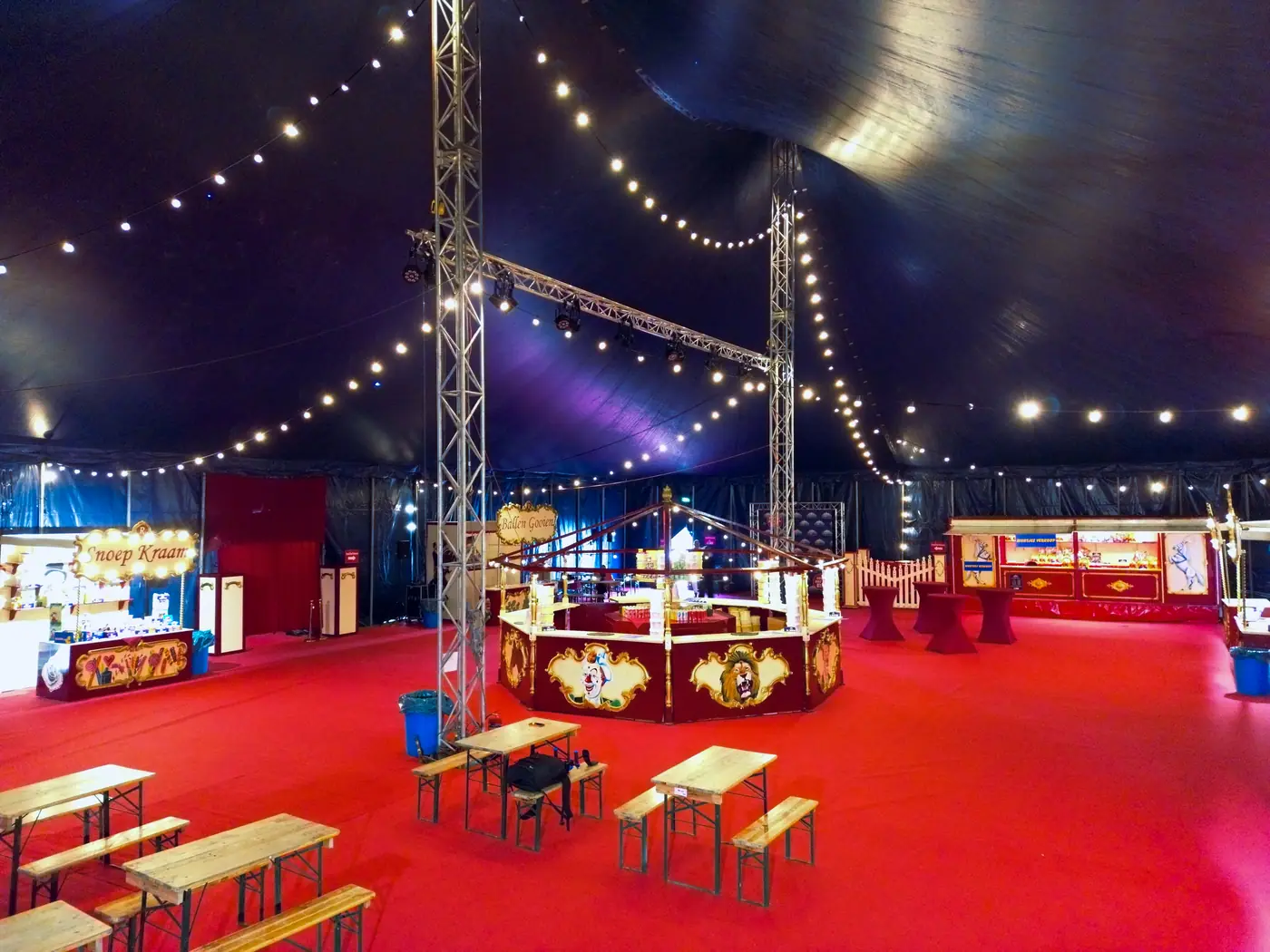 De foyertent met slingers van lampjes, rode loper en houten tafels